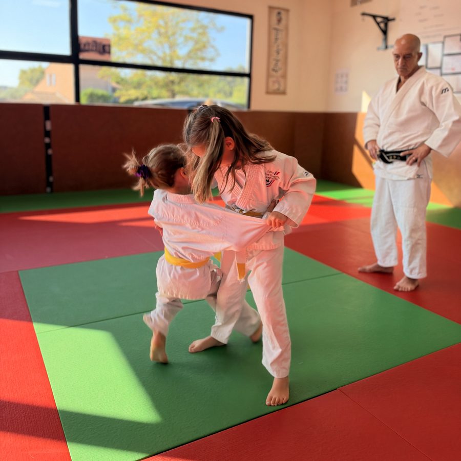 Deux jeunes judokas à l'entraînement sous le regard de leur professeur